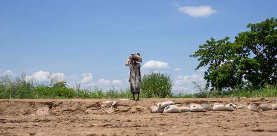 A woman walks across dry land