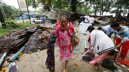 Woman walking amongst debris Indonesia tsunami