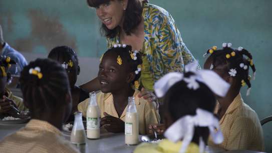 Kathy Childress stands among a group of school children working at their desks in Haiti