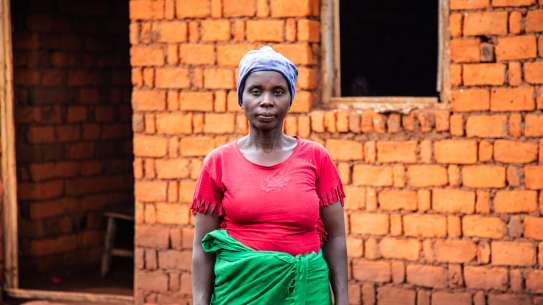Woman standing in front of her home in Burundi