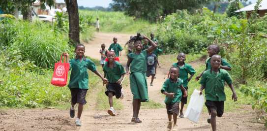 A group of children in their school uniforms, running towards the camera