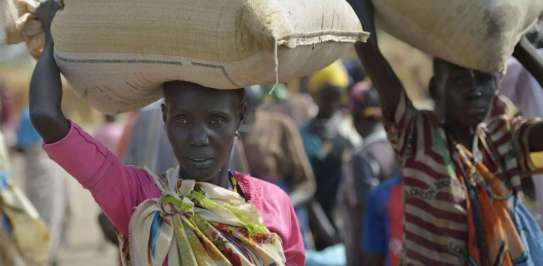 A displaced woman carries a bag of grain in South Sudan