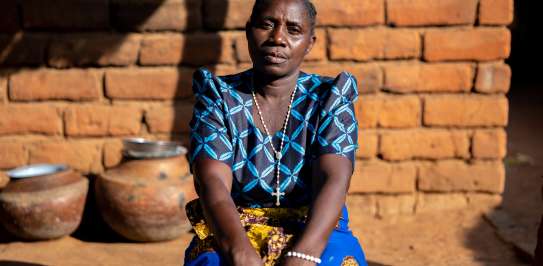 Woman sits beside house in Malawi