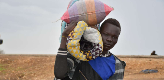 A young man arriving at the Joda border, in South Sudan, carrying his belongings on his shoulder