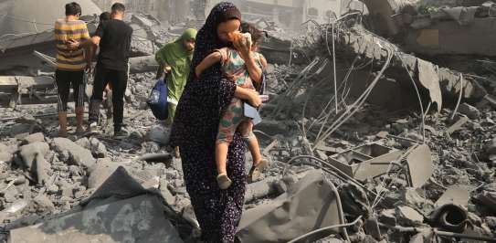 woman cradles child amongst rubble