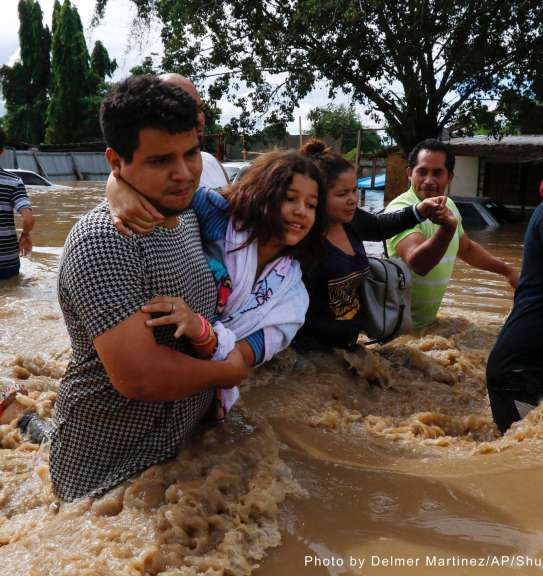 People help each other wade through a flooded street in the aftermath of Hurricane Eta in Jerusalen, Honduras, not long before a second hurricane, Iota, hit two weeks later. 