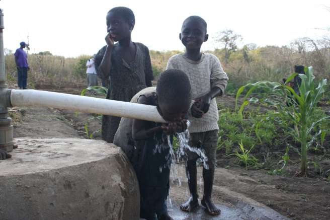 Children drink from a functioning water well in  Kannkuala village, Mzimba District.