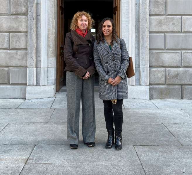 2 Women standing outside grey building