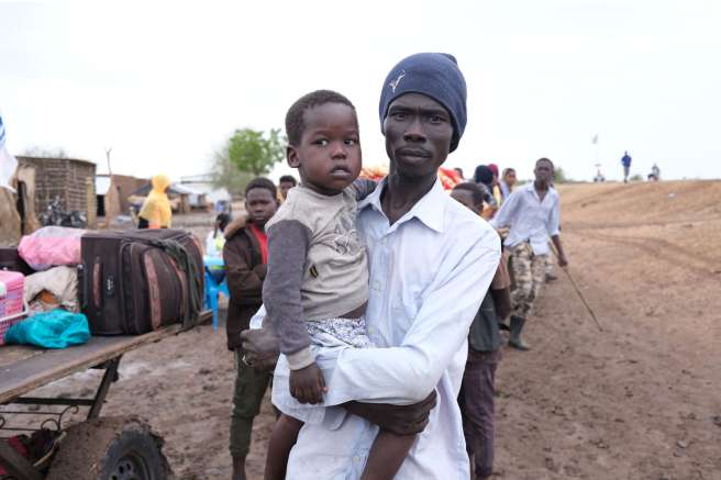 Man holds son after having just crossed from Sudan into South Sudan 