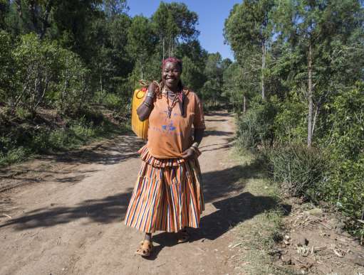 Kawite walks down a path in ethiopia carrying water due to climate crisis