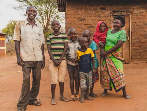Faith Muvili poses with her family (husband and 5 children) in front of their house.