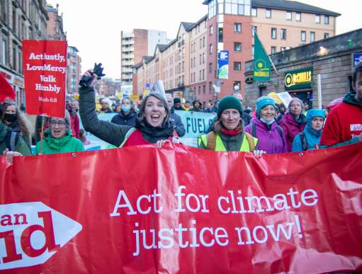 A group marches with a banner saying "Act for climate justice now!"