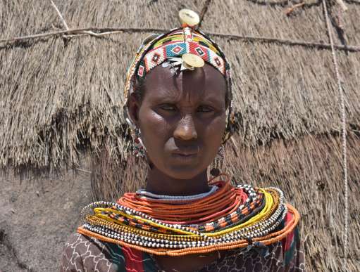 Woman wearing tribal clothes in front of hut