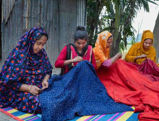  Kakoli Khatun sit son the floor sewing in her courtyard with three other women