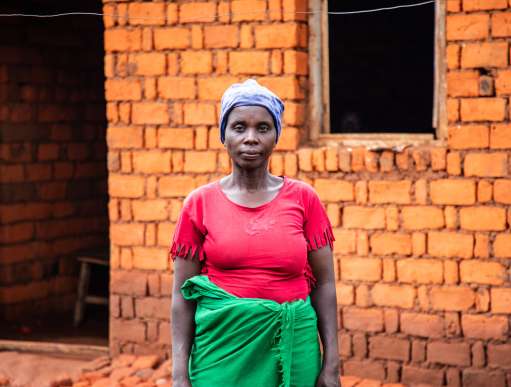 Woman standing in front of her home in Burundi
