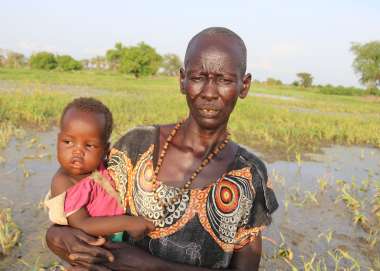 Asunta stands in her flooded farm in South Sudan