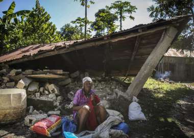 Woman sits in front of a destroyed house after the earthquake in Camp-Perrin, Les Cayes, Haiti