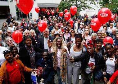 Large group of smiling supporters holding red Christian Aid balloons