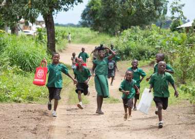 A group of children in their school uniforms, running towards the camera