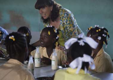 Kathy Childress stands among a group of school children working at their desks in Haiti