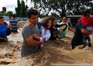 People help each other wade through a flooded street in the aftermath of Hurricane Eta in Jerusalen, Honduras, not long before a second hurricane, Iota, hit two weeks later. 