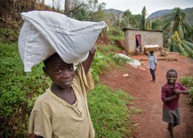 Three boys carry home emergency aid kits after Hurricane Matthew in Haiti