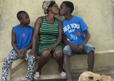 Haitian family sat down for a photo with eldest child kissing mother on her cheek