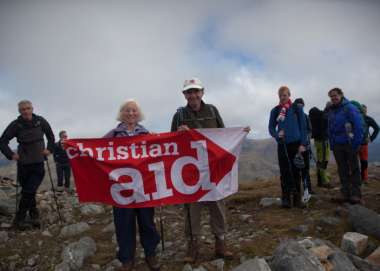 Christian Aid supporters on a mountain holding up a banner